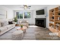 Bright living room with fireplace, large windows, ceiling fan and modern furnishings. Staged for sale at 7301 Pebblestone Dr # F, Charlotte, NC 28212