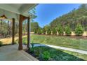 Covered front porch with natural wood pillars and view of the landscaped front yard with lush greenery at 8225 Long Island Rd, Catawba, NC 28609