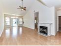 Bright living room with fireplace, wood floors, ceiling fan, and large windows to let in plenty of light at 11705 Silverado Ln, Charlotte, NC 28277