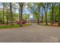 An elegant home with a long brick driveway, surrounded by mature trees and lush landscaping at 1441 Carmel Rd, Charlotte, NC 28226