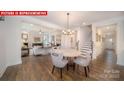 Open concept view of the dining room with a hardwood floor and views to the kitchen and living room at 156 Asmodean Ln, Troutman, NC 28166