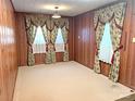 Empty living room with wood paneling and decorative curtains creating a cozy and vintage feel at 215 Old Dixie Rd, Lancaster, SC 29720