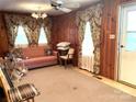 Cozy living room features wood paneling, floral curtains, and comfortable seating at 215 Old Dixie Rd, Lancaster, SC 29720