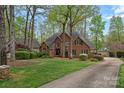Stately red brick home with a long driveway, lush lawn, and mature trees creating a private setting at 276 Greyfriars Rd, Mooresville, NC 28117