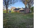 Spacious backyard view with mature trees, a screened porch, and lush green grass at 3025 School St, Claremont, NC 28610