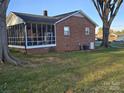 Back of brick home featuring a screened in porch and a well-maintained lawn at 3025 School St, Claremont, NC 28610
