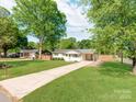 Charming single-story home with well-manicured lawn, mature trees, and a welcoming covered parking area at 4303 Greenhaven Ln, Gastonia, NC 28056