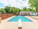 Inviting in-ground pool with diving board, surrounded by concrete patio and greenery at 4303 Greenhaven Ln, Gastonia, NC 28056