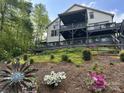 A scenic shot of the home's exterior featuring lush greenery, a yard, and an expansive deck at 5888 Wood Duck Way, Catawba, NC 28609
