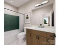 Modern bathroom features green tiled accent wall, wood vanity, and sleek black hardware at 8048 Cedarsmith Ct, Charlotte, NC 28217