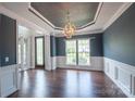Formal dining room with dark blue walls, white trim, hardwood floors and a decorative chandelier at 8810 Cool Meadow Dr, Huntersville, NC 28078