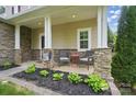 Inviting front porch with stone accents, comfortable seating, and a beautifully landscaped garden bed at 9312 Seamill Rd, Charlotte, NC 28278