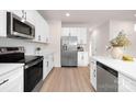 Bright kitchen featuring white cabinetry, stainless steel appliances, and a view of the hardwood floors at 103 Webb St, Mount Holly, NC 28120