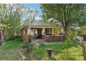 Brick home with a covered porch, mature landscaping, and a classic American flag, showcasing cozy charm at 115 E 11Th St, Salisbury, NC 28144