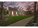 Beautiful brick home with a covered front porch, manicured lawn, and lovely landscaping at sunset at 135 Northbridge Dr, Mooresville, NC 28115