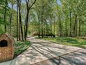 Long driveway leading to a traditional brick home, surrounded by mature trees at 1413 Willow Oaks Trl, Weddington, NC 28104