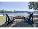 Scenic waterfront view with Adirondack chairs around a fire pit, and a private dock on the lake at 143 S Gibbs Rd, Mooresville, NC 28117