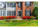 Close-up of a home's front exterior with a beautiful yard and blooming red bushes leading up to a black front door at 16718 Hampton Crossing Dr, Huntersville, NC 28078