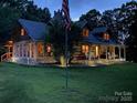 Inviting log home at twilight featuring a charming front porch and lush lawn at 3014 Haigler Rd, Monroe, NC 28110