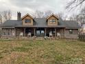 Charming log cabin with covered porch and seating, surrounded by a serene landscape at 3014 Haigler Rd, Monroe, NC 28110
