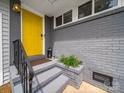 Inviting front porch with a vibrant yellow door, gray brick siding, and sleek black railing at 4024 Seaforth Dr, Charlotte, NC 28205