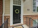 Elegant black front door with a wreath, sidelight window, and brick accents exuding curb appeal at 668 Sixth Baxter Xing, Fort Mill, SC 29708