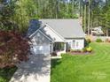 Aerial view of a well-kept home with lush green lawn, a driveway, and surrounded by beautiful trees at 8707 Copenhagen Ln, Charlotte, NC 28216