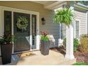 Inviting front porch featuring a decorated door, a fern, potted plants, and stylish decor at 8707 Copenhagen Ln, Charlotte, NC 28216