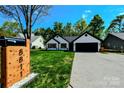 Inviting single-story home with well-manicured lawn, wooden shutters, a black roof and a striking mailbox at 8811 Steelechase Dr, Charlotte, NC 28273