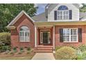 Inviting front entrance features a classic brick facade, covered porch, and meticulously maintained landscaping at 1090 Heather Glen Dr, Matthews, NC 28104