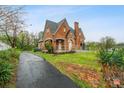 Exterior view of a brick home with a driveway, mature trees, and a well-maintained lawn at 115 12Th Sw St, Hickory, NC 28602