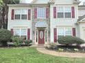 Welcoming home exterior with a red front door, stone accents, and manicured landscaping at 119 W Maranta Rd, Mooresville, NC 28117