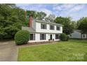 Beautifully landscaped two-story home with black shutters, well maintained lawn, and large shade trees at 2413 Bergen Ct, Charlotte, NC 28210