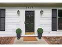 Close up of the front door with black hardware, sconces, and symmetrical potted greenery at 2413 Bergen Ct, Charlotte, NC 28210
