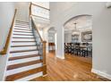 Open foyer with hardwood floors, staircase with metal spindles, and arched doorways to other rooms at 5103 Trinity Trace Ln, Monroe, NC 28110