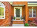 Inviting front entrance with brick steps and black door, framed by potted plants and detailed molding at 5103 Trinity Trace Ln, Monroe, NC 28110