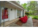 A well lit and clean entryway with a red front door and white brick walls and trim, bordered by azaleas at 6815 Old Post Rd, Charlotte, NC 28212