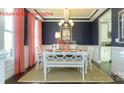 This dining room has navy walls, white trim, modern chandelier, and a neutral rug at 7023 Butternut Oak Ter, Huntersville, NC 28078