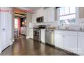 Well-equipped kitchen with stainless steel appliances, white cabinets, granite countertops, and dark hardwood flooring at 7023 Butternut Oak Ter, Huntersville, NC 28078