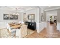 Dining room with decorative wainscoting, wood floors, elegant chandelier, and view leading into a living room at 7031 Butternut Oak Ter, Huntersville, NC 28078