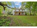 Beautiful home featuring a large manicured lawn, mature trees, and an inviting front porch with classic columns at 740 Woodlawn Ave, Mount Holly, NC 28120