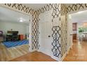 Hallway with patterned wallpaper, wood floors, and views into adjacent rooms at 7514 Pewter Ln, Charlotte, NC 28270