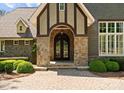 Elegant entrance with arched doorway, stone accents, and lush landscaping at 10915 Hermit Thrush Ln, Charlotte, NC 28278