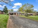 Long driveway leading to a brick ranch home with covered parking and lush green lawn at 1309 Briarcliff Rd, Shelby, NC 28152