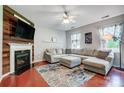 Comfortable living room with a decorative fireplace, flat screen TV, plush sectional, and hardwood floors at 13715 Sunrise View Dr, Charlotte, NC 28278