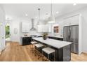 Modern eat-in kitchen with stainless steel appliances, a large island, pendant lighting, and black and white cabinets at 2008 St John St, Charlotte, NC 28216