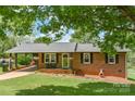 Lovely brick home features a welcoming porch, stylish black shutters, and lush front lawn at 205 Cooke Cir, Kings Mountain, NC 28086