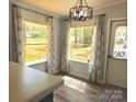 Eat-in kitchen area with large windows, modern lighting, wooden floors and stylish patterned curtains at 3325 Stony Brook Cir, Newton, NC 28658