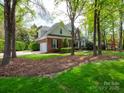 Brick home with three car garage, a well-manicured lawn, and mature trees at 4721 Myers Ln, Harrisburg, NC 28075