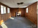 Spacious living room featuring wood paneled walls, carpeted floor, and brick fireplace at 539 Jennings Rd, Statesville, NC 28625